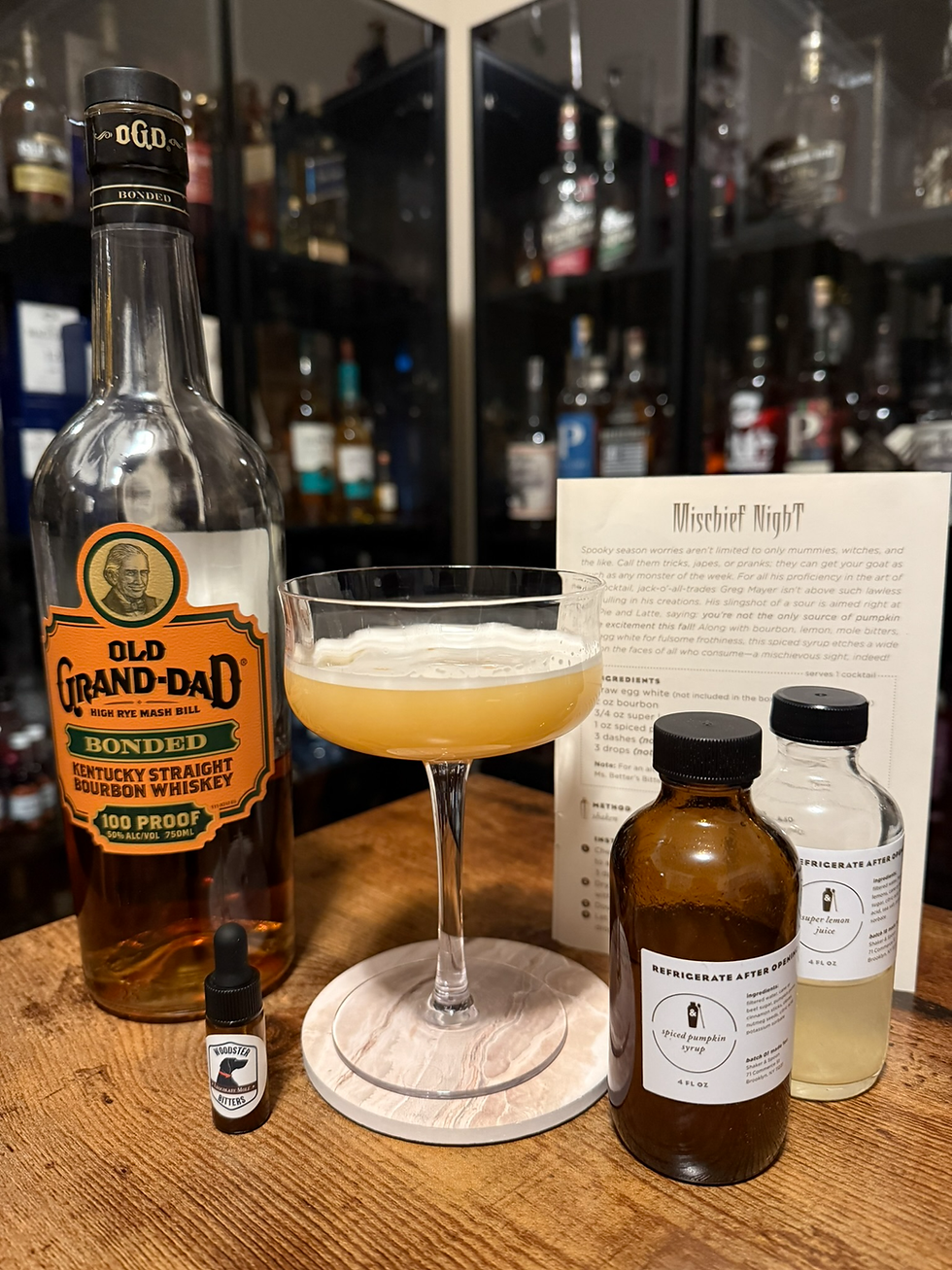 Cocktail setup with Old Grand-Dad bourbon, bitters, pumpkin syrup, lemon juice, and a coupe glass beside a Mischief Night recipe card.