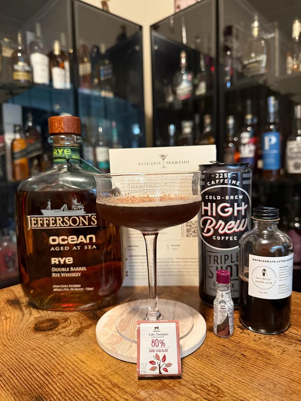 Cocktail setup on a wooden table with Jefferson’s Ocean rye, High Brew cold brew, dark chocolate, and a martini glass in a home bar.