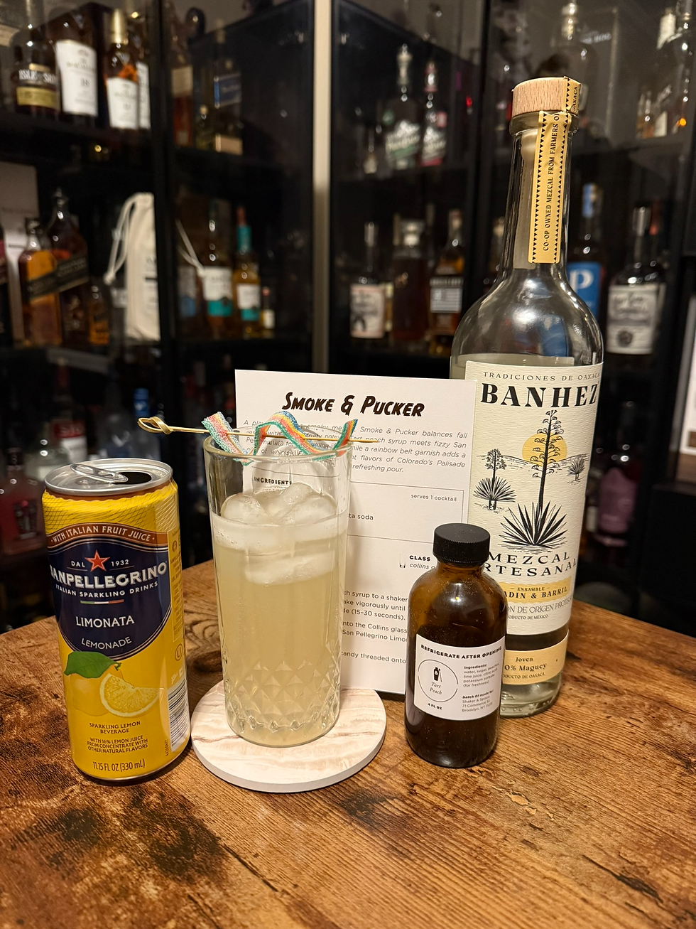 Cocktail setup with mezcal, Lemonata, syrup, and a rainbow-garnished drink beside a Smoke & Pucker recipe card.