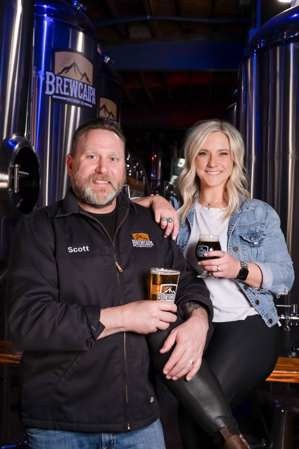 a man named scott stands next to a woman holding a glass of beer