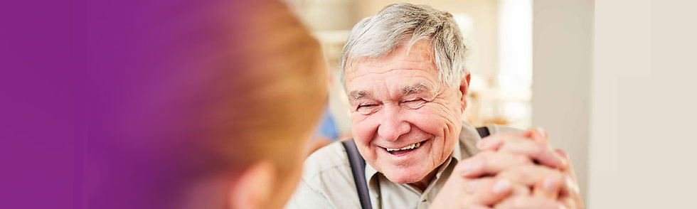 Old man smiling in conversation with carer.