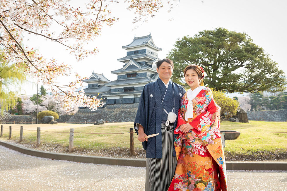 松本城前で桜と一緒に写る新郎新婦
