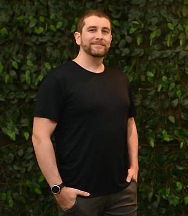 Lucas da Rosa Ruhe, psicólogo clínico, em foto de formatura com fundo verde e letreiro “Formei”
