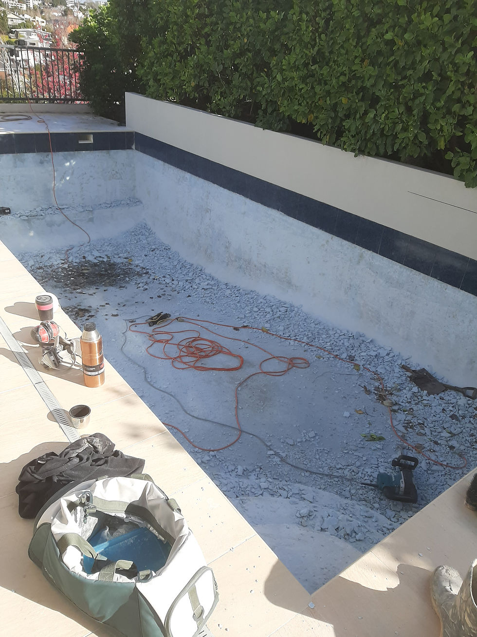Wide-angle view of an empty concrete swimming pool under refurbishment.