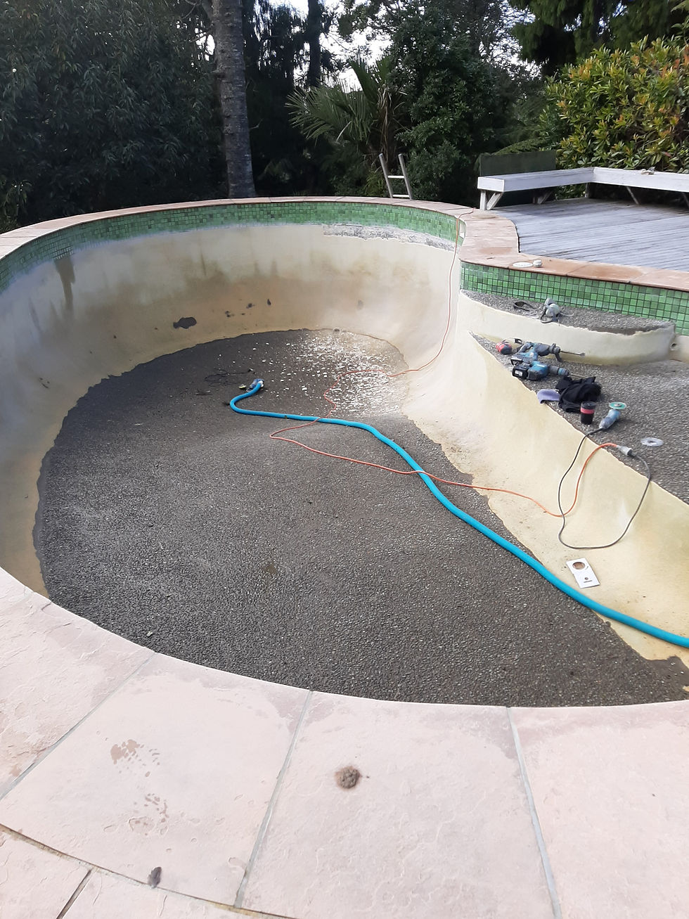 Wide-angle view of an empty concrete swimming pool shell being inspected before plastering