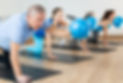 Diligent elderly man practicing pilates with ball in exercise room during pilates classes.