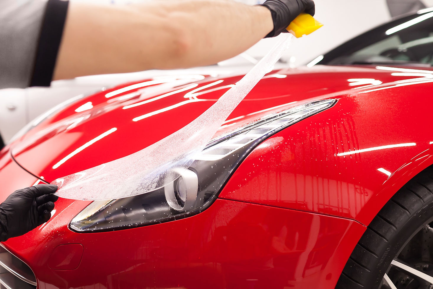 Red car having paint protection film applied to a headlight