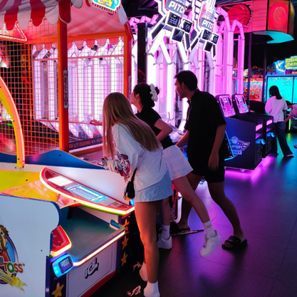 People playing arcade games inside a compact indoor family entertainment center with brightly lit machines and a small-format layout.
