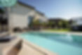 Gepflegter Garten mit verschiedenen Liegemöglichkeiten, Pflanzen und einem hellen Pool im Vordergrund.