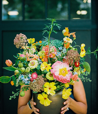 large flower arrangement with butterfly ranunculus, peonies, pears and zinnias in a brass urn