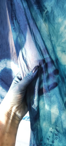 Main sur soie aux nuances de bleues dans un rayon de lumière.