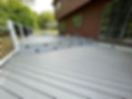 Multi-level gray deck with white railing, steps, and brown house
