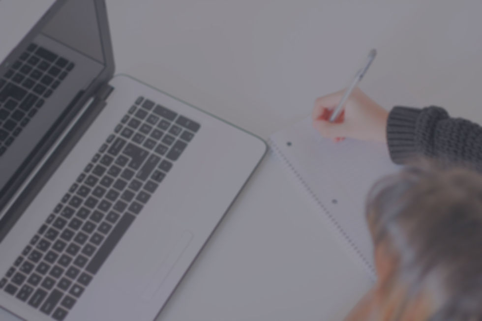 Girl taking note next to a laptop