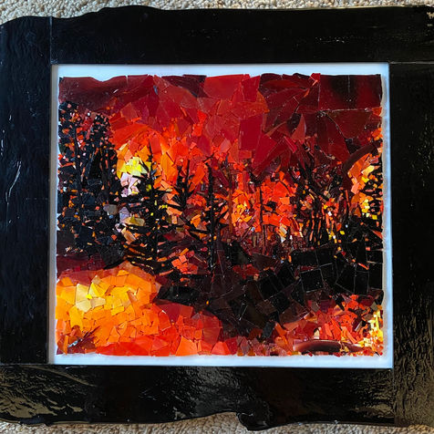 Stained-glass mosaic of wildfire with orange, red, and yellow glass passages moving through darker surrounding forms.