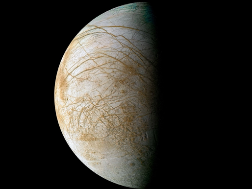 Europa's icy surface with brown streaks is half-lit against a black space background. The image captures a serene, celestial mood.