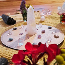 Bergkristalle und rote Blüten auf einem runden Holzteller, kunstvoll arrangiert.