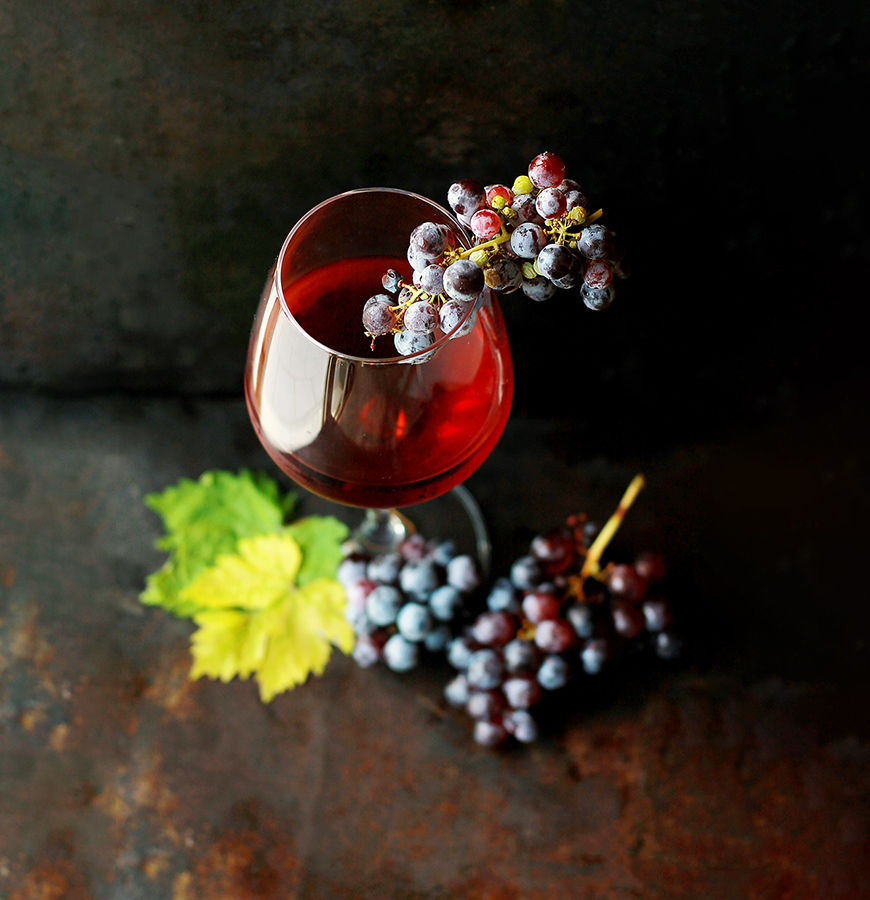 Wineglass filled with wine and grapes around the base with leaves to help visualize the wine trail.