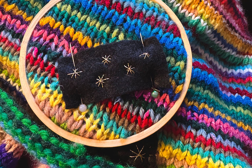 gold embroidered patch on colorful knitted blanket in embroidery hoop