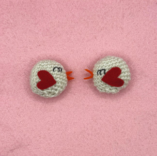 two white crochet birds on a pink background