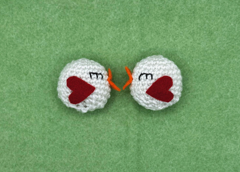 Two white crochet birds on a green background