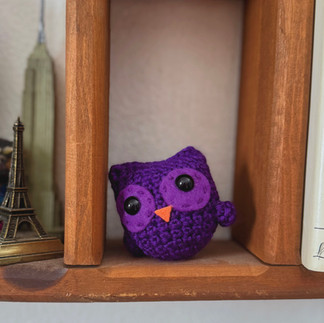 tiny purple crochet owl on shelf with mini empire state building in the background