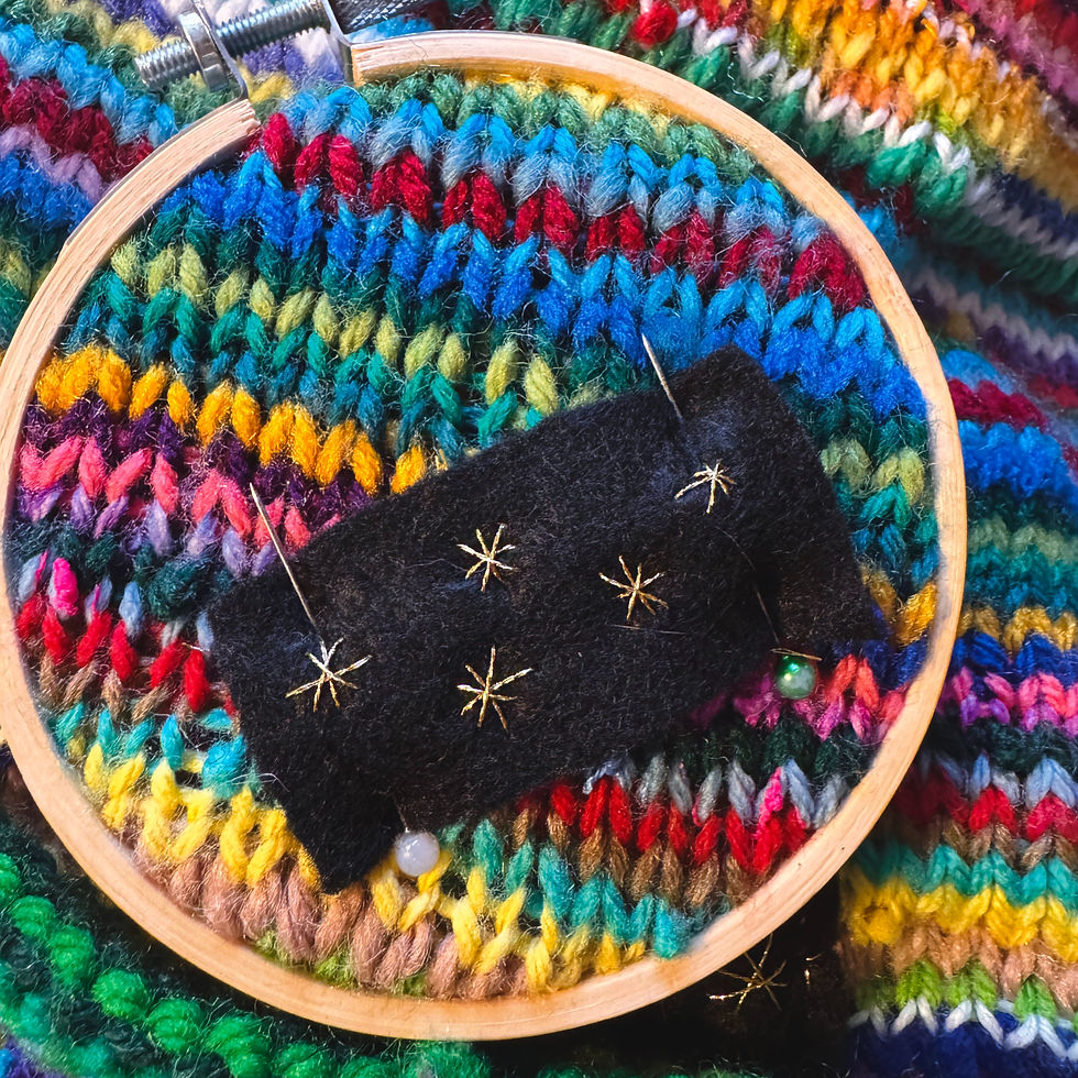gold embroidered patch on colorful knitted blanket in embroidery hoop