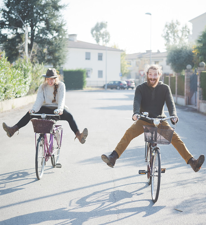 A man and woman smiling and laughing while riding bicycles in a very carefree way