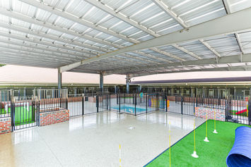 Wide shot of epoxy-floored, steel-roofed covered play yard connected to main boarding building.