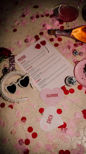 Table setting with menu, name tags, glasses, and scattered confetti. Quirky Wedding Stationery.