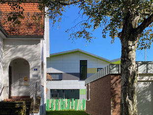 Durchgang KITA Sternenzelt. Weißes Gebäude, grünes Dach. Entworfen vom Architekten Johann Eisele aus Darmstadt
