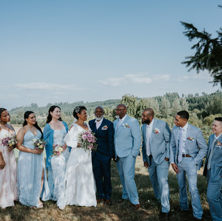 Diverse wedding party, bride and groom, smiling under sunny sky.