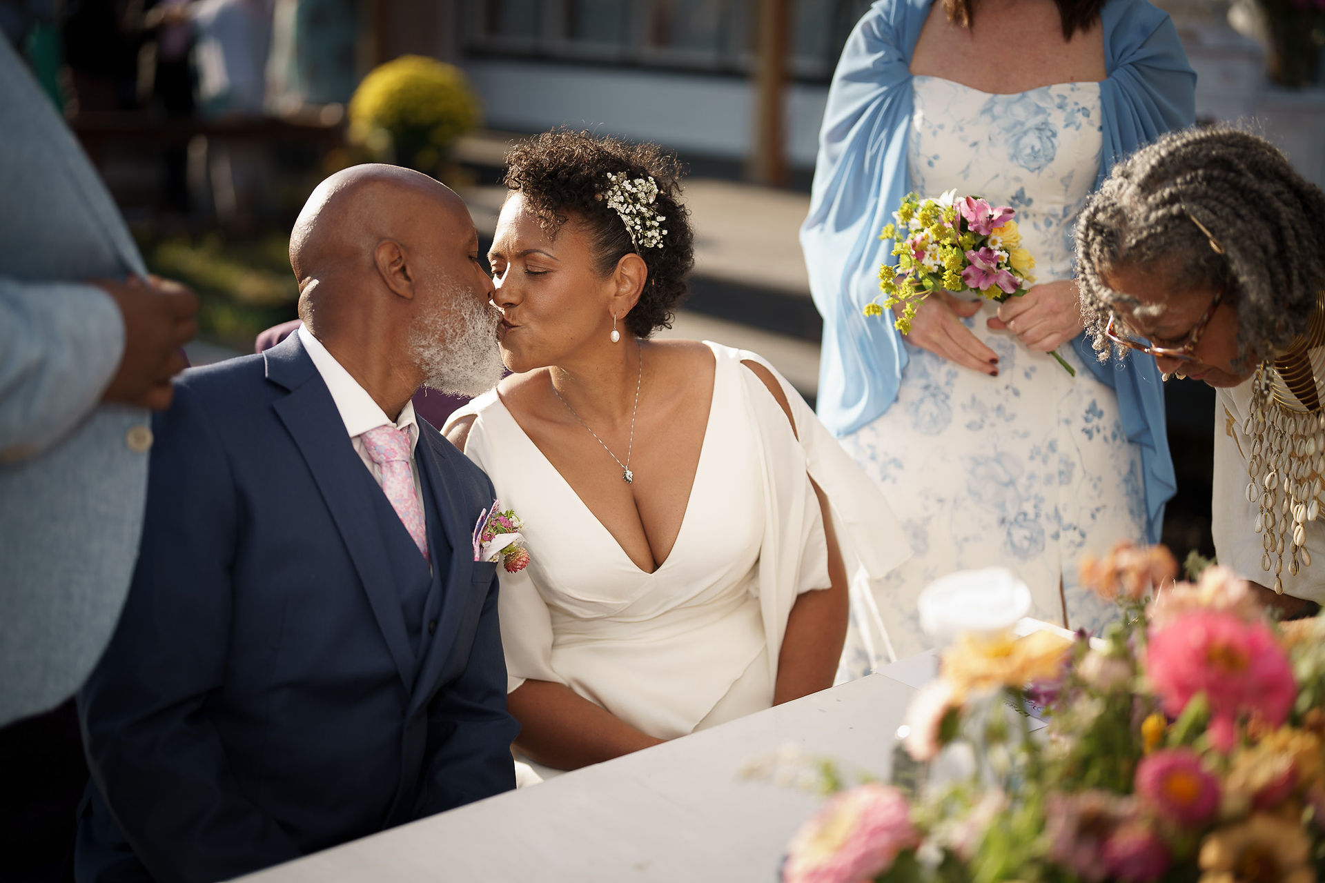 Happy bride kisses groom's cheek at their intimate outdoor farm wedding.