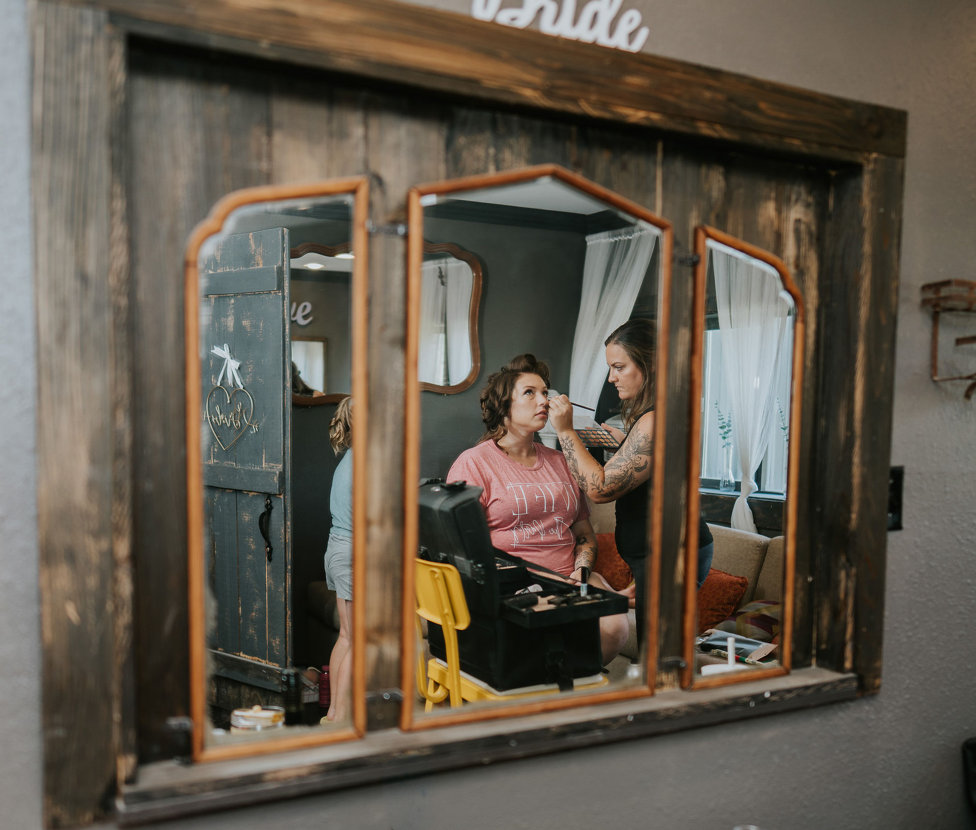 Bride getting makeup done, 'bride' text, reflected in rustic mirrors.