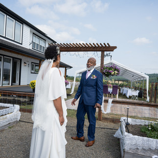 Bride and man in suit smiling happily at intimate farm wedding.