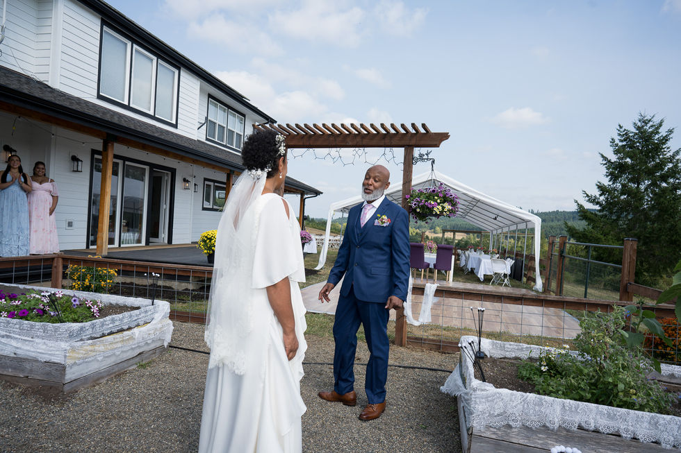 Bride and man in suit smiling happily at intimate farm wedding.
