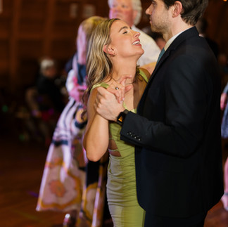Smiling couple dancing intimately at a lively wedding reception.