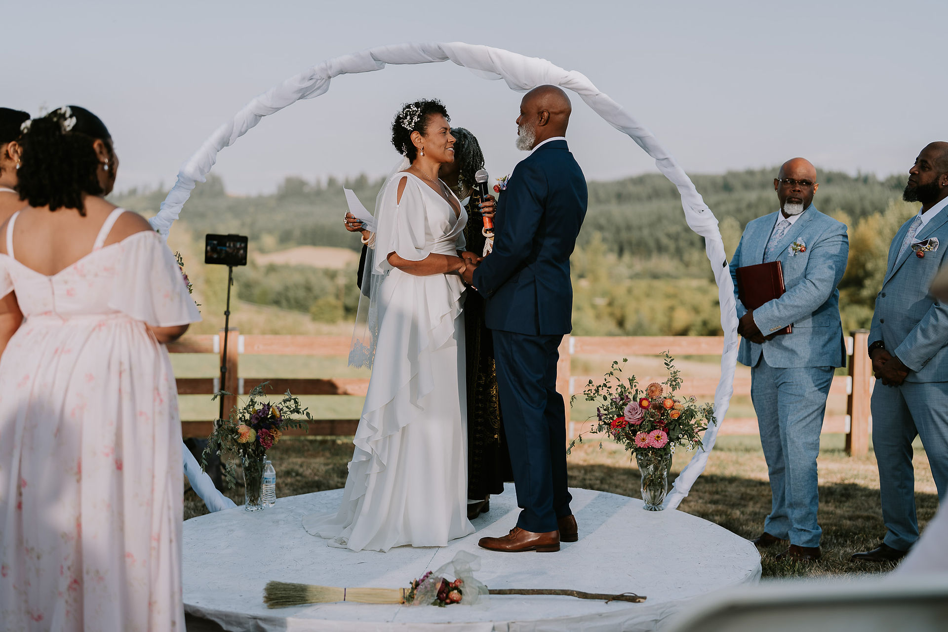 Couple exchanging vows under arch at intimate farm wedding.