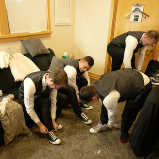 Four groomsmen tying their shoelaces