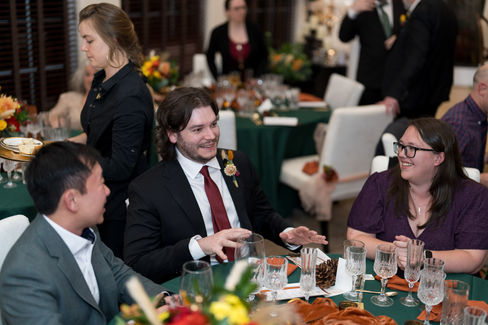 Man in suit talking at a fall wedding reception table with guests.