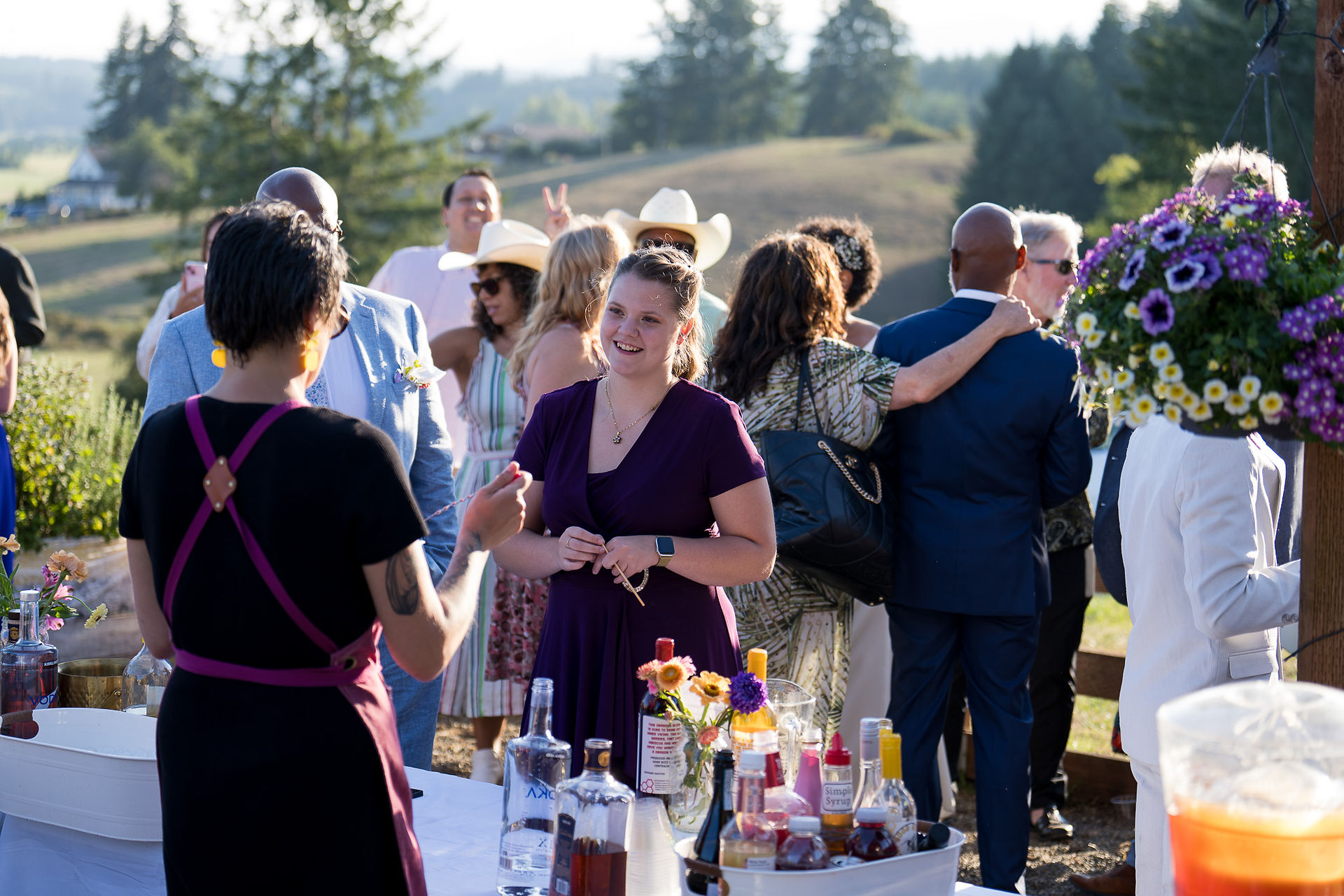 Smiling woman in purple, guests at Intimate Farm Wedding reception drinks.