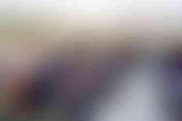 Smiling bride and groom seated among guests at outdoor wedding.