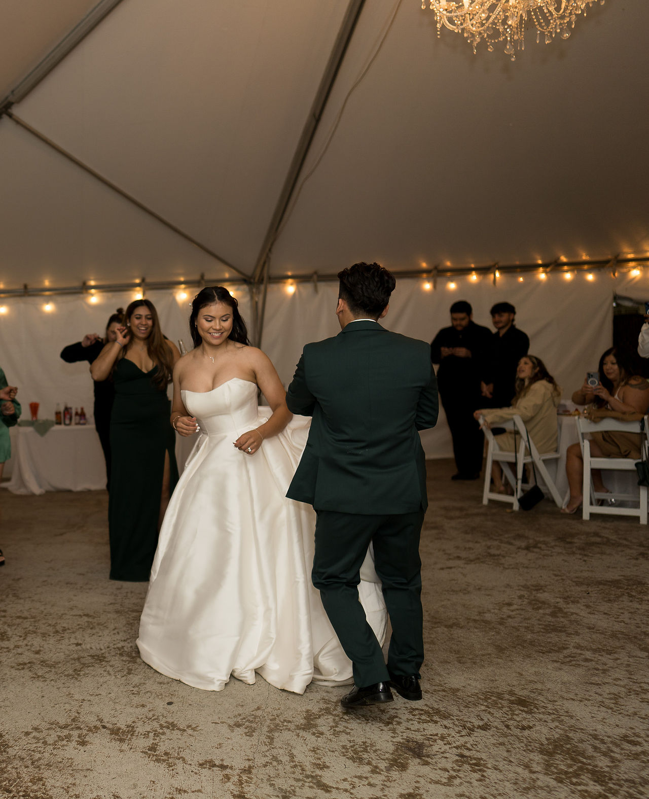 Bride and groom happily dancing at their wedding reception under a tent.
