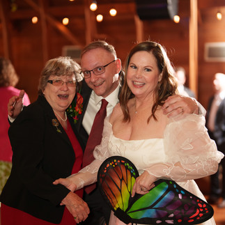 Smiling couple and guest with colorful butterfly fan at reception.