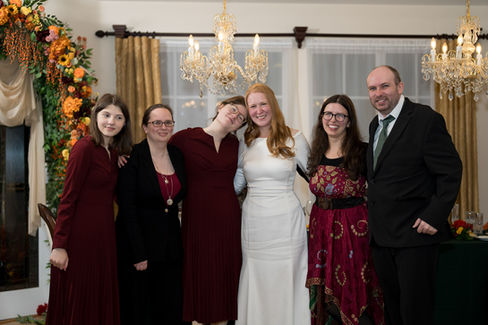 Smiling group of six people, including a bride in white dress.