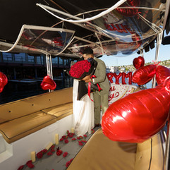 Romantic boat proposal: Couple embraces amidst red roses and balloons