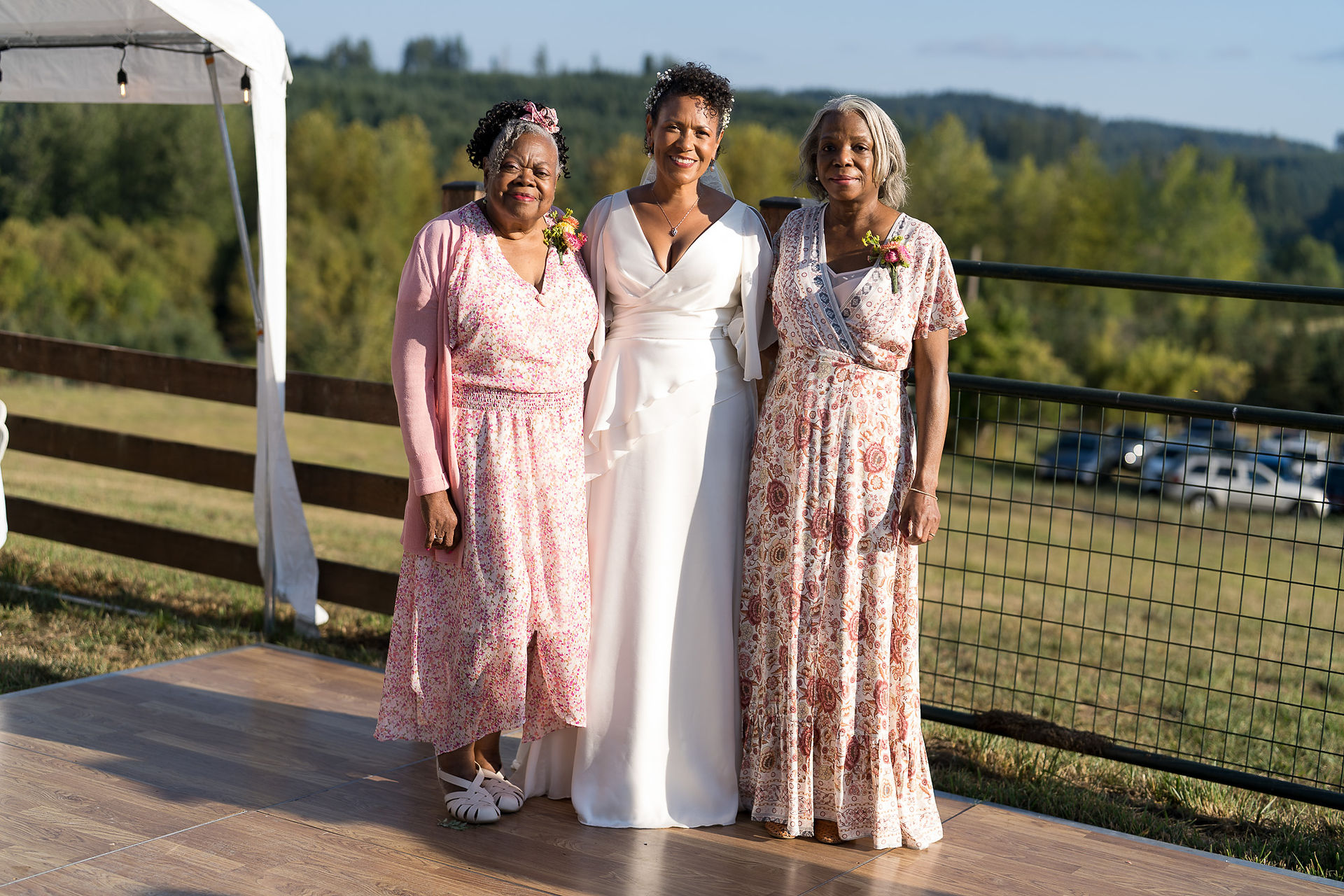 Bride and two women posing at an intimate farm wedding.