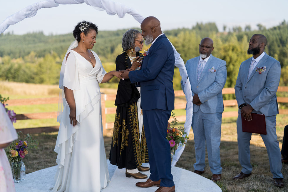 African-American couple exchanging rings at their outdoor wedding ceremony