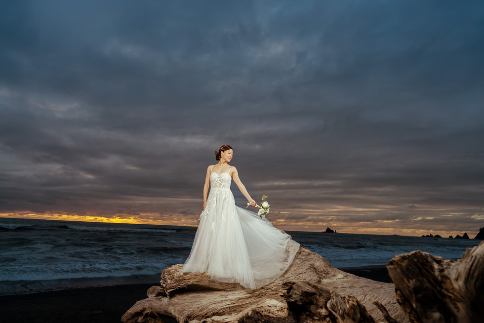 Bride in white dress on driftwood at Olympic National Park elopement