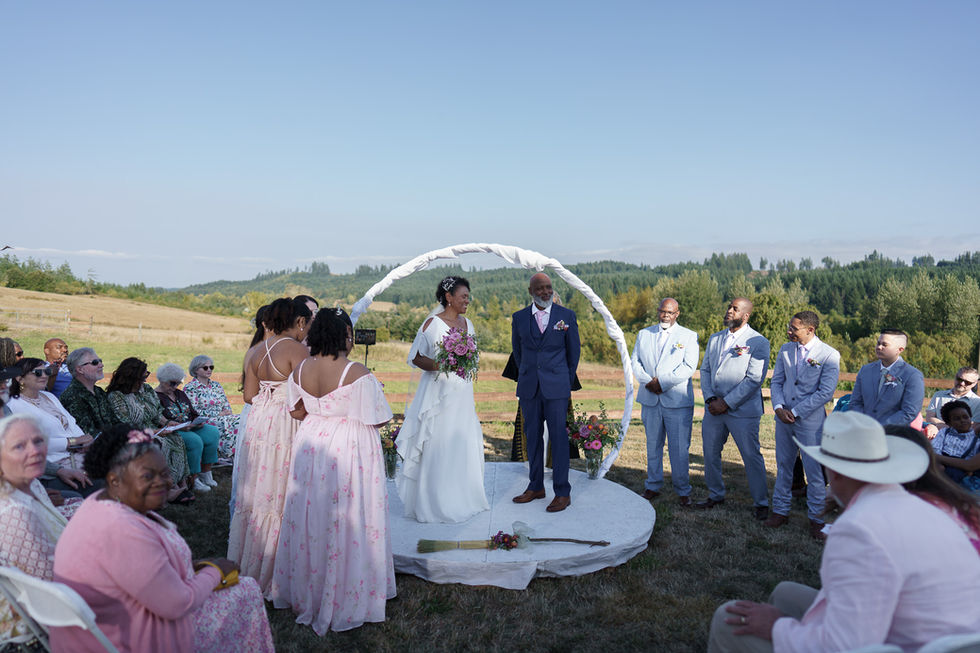 Bride and groom under arch during their outdoor countryside wedding.