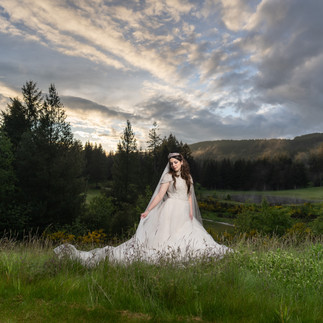 Bride in white gown and veil in grassy field at Gold Mountain Golf Club